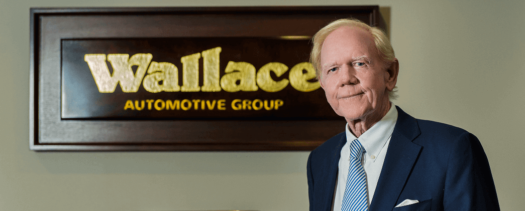 Bill Wallace stands in front of Wallace Automotive Group sign in Stuart, FL